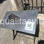 Imagen de una mesa con la escultura en relieve de la fachada de la casa. Incluye código QR.