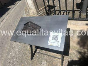 Imagen de una mesa con la escultura en relieve de la fachada de la casa. Incluye código QR.