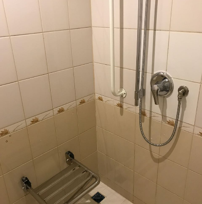 Ducha encastrada con asiento abatible fijado en la pared.