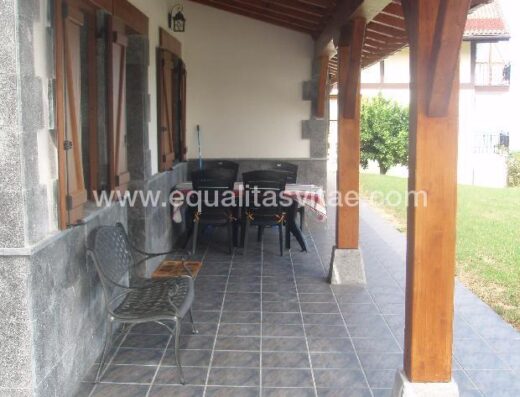 Porche equipado con mesa y sillas de terraza accesibles en la entrada a la casa.
