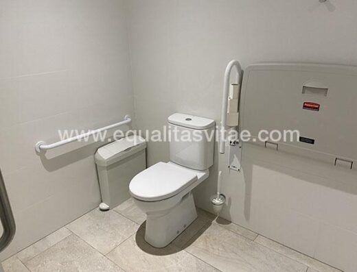 Baño accesible con barras de apoyo a ambos lados