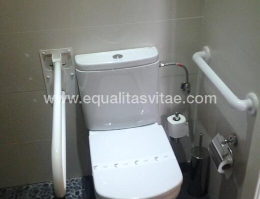 Inodoro con barras de apoyo en baño habitación accesible