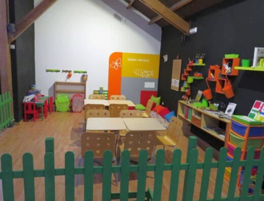 Sala infantil multiusos con pequeñas mesas y sillas.