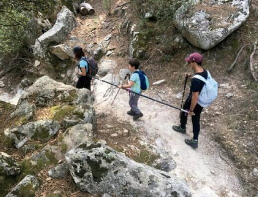 Tres personas en travesía montañosa con barra direccional.