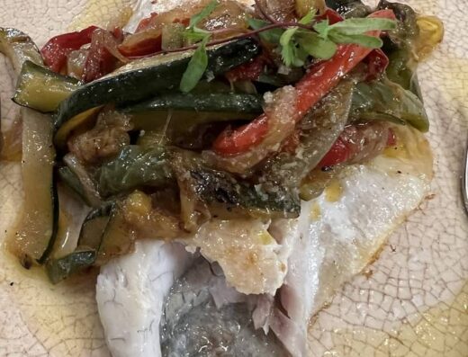 Lomo de pescado con verduras sobre él.