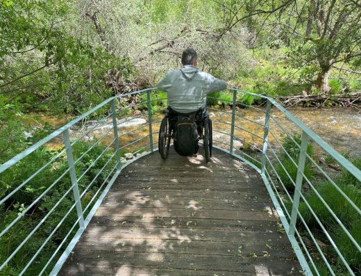 Imagen de usuario de silla de ruedas junto a mirador en el río.