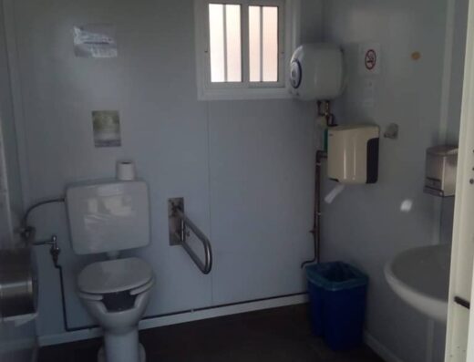 Interior del aseo, inodoro con barras de apoyo.