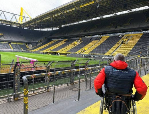 Usuario de silla de ruedas recorriendo pasillo del estadio.