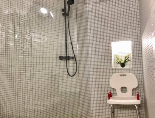 Ducha a cota cero con mampara y silla para la ducha.