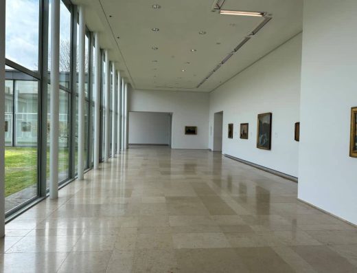 Galería con cuadros y un gran ventanal.