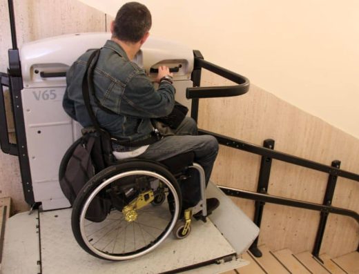 Usuario de silla de ruedas en plataforma salvaescaleras.