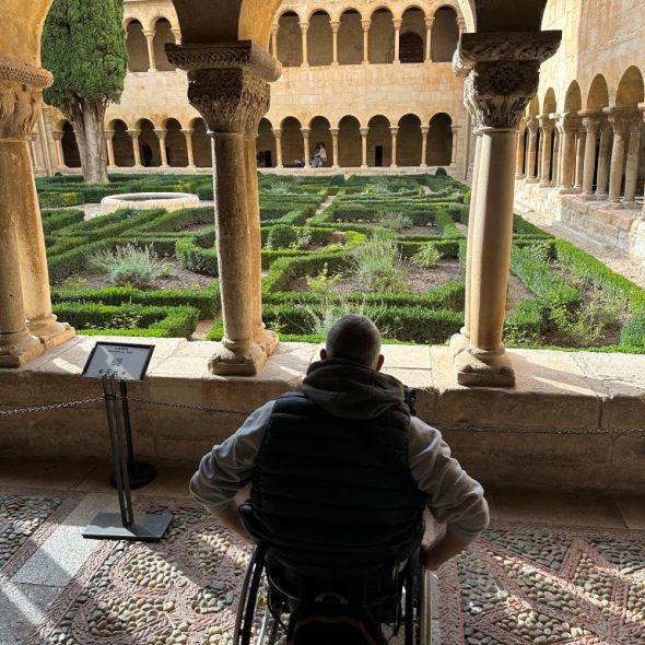 Imagen de usuario de silla de ruedas en el claustro mirando el jardín.