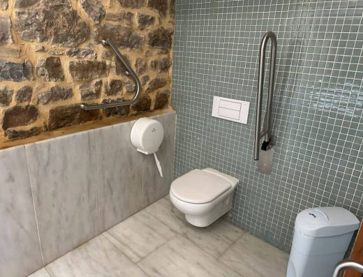 Imagen de baño adaptado, inodoro con barras de apoyo.