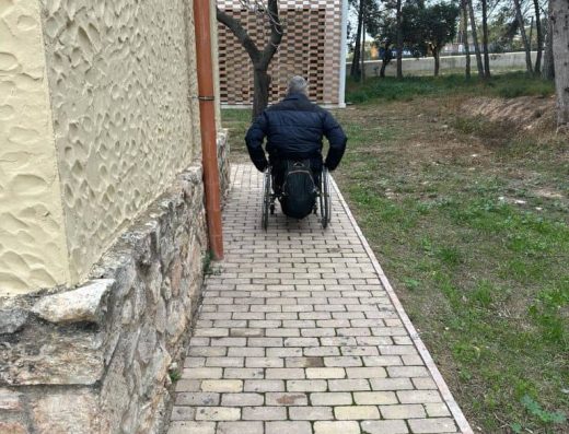 Imagen de usuario de silla de ruedas transitando por acera.