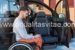 Imagen de usuario de silla de ruedas junto a un vehículo.