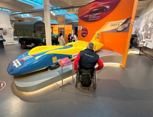 Imagen de usuario de silla de ruedas junto a coche futurista.