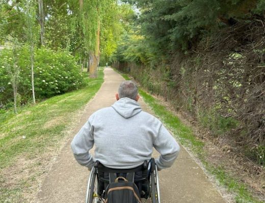 Imagen de usuario en silla de ruedas rodando por el paseo