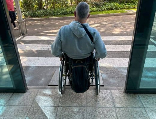 Imagen de persona usuaria de silla de ruedas saliendo del hotel por entrada a cota cero