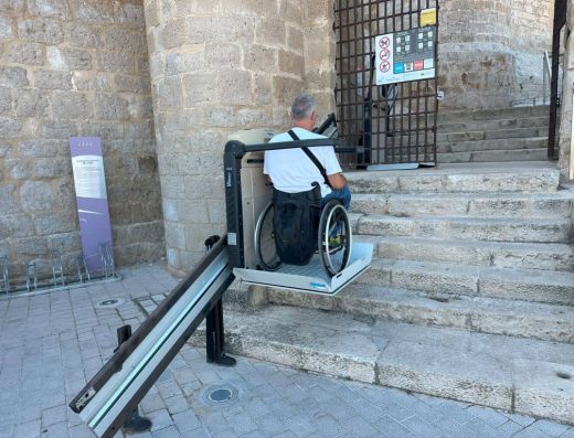 Imagen de ususario en silla de ruedas utilizando la pltaforma salva escalera para acceder al museo provincial del vino