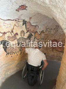 Imagen de usuario de silla de ruedas en una recreación de una cueva con pinturas rupestres.