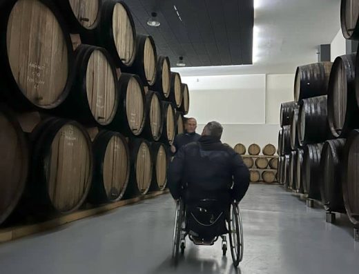 Imagen de una persona en silla de ruedas recorriendo la nave de barricas.