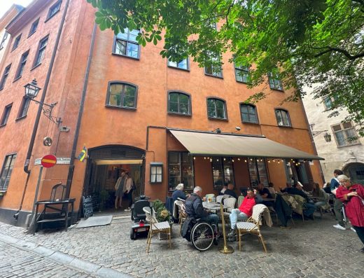 Imagen de la terraza exterior del restaurante con una persona usuaria de silla de ruedas en una de las mesas.