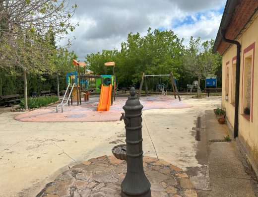 Imagen del exterior del centro con una fuente y un parque infantil.