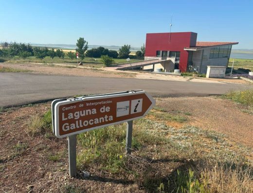 Imagen de un panel direccional que indica la OT de Gallocanta. El edificio que la alberga al fondo.