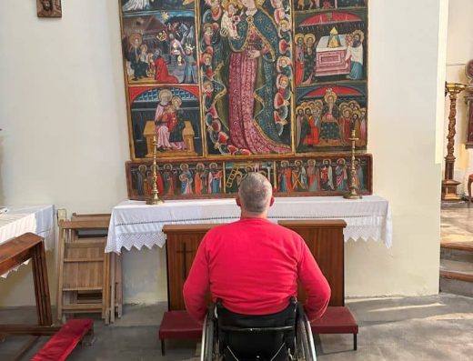 Imagen de una persona usuaria de silla de ruedas observando el retablo gótico.