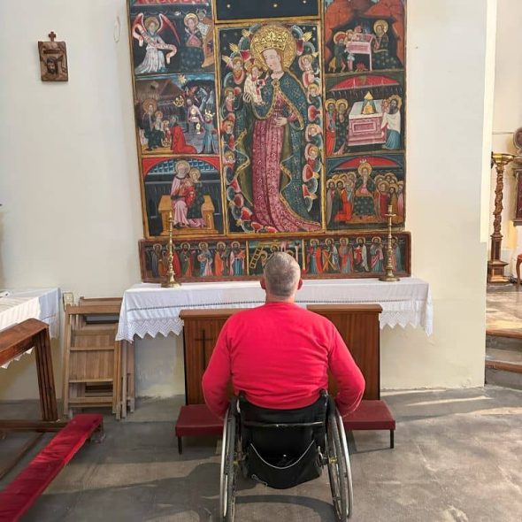 Imagen de una persona usuaria de silla de ruedas observando el retablo gótico.