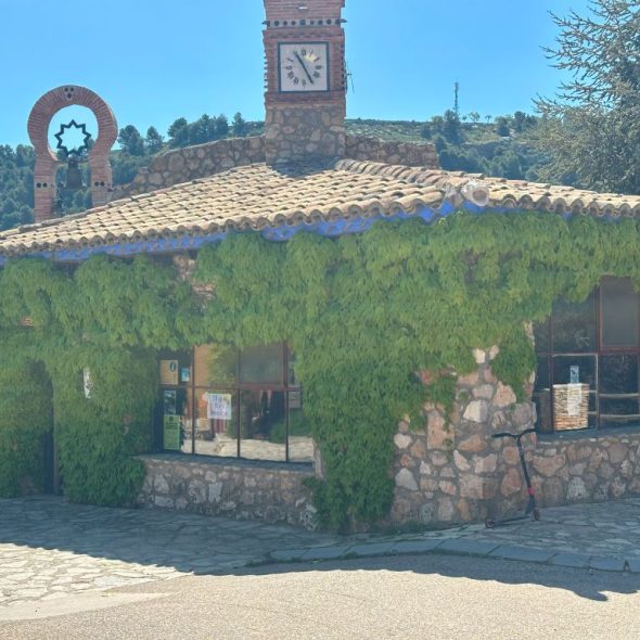 Imagen panorámica de la oficina de turismo con enredaderas en su fachada.