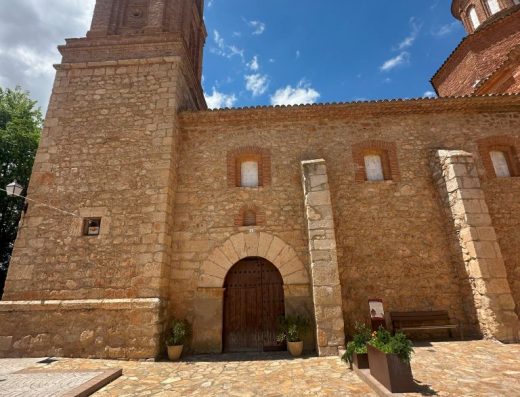 Imagen panorámica de la fachada principal de la iglesia con torre campanario.