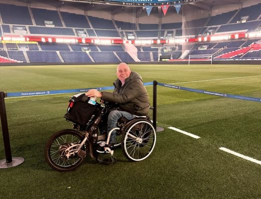 Imagen de una persona en silla de ruedas sobre el césped del campo de fútbol.
