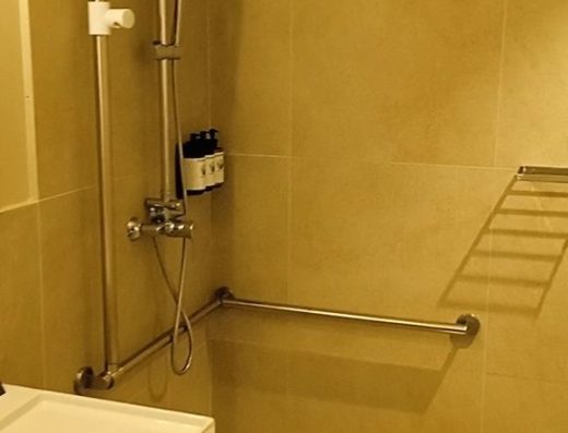 Imagen de la ducha a cota cero con taburete y barras de apoyo.