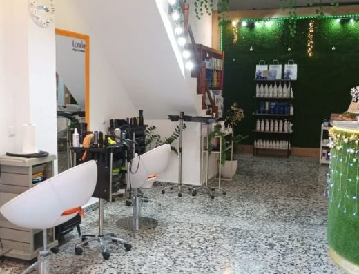 Imagen del interior del local, a la derecha el mostrador de recepción y a la izquierda dos sillas con espejo frente a cada una de ellas.