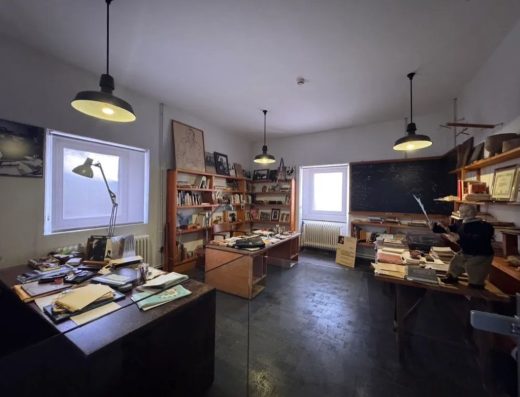 Imagen del interior de un estudio con mesas repletas de documentos, estanterías con libros etc.