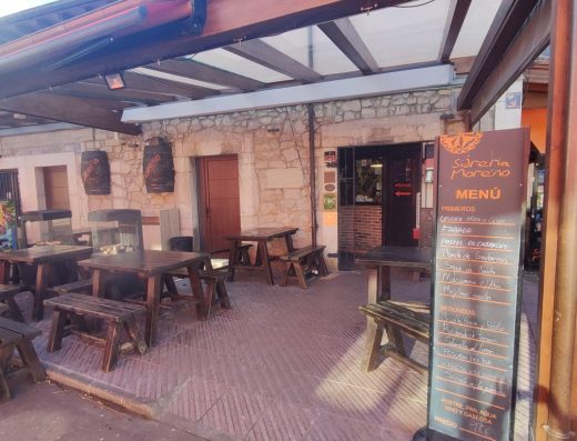 Imagen de la entrada a la sidrería con terraza exterior con mesas tipo merendero.