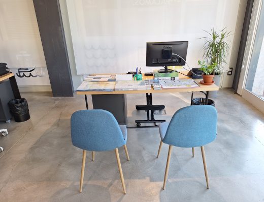 Imagen de un punto de atención en la oficina de turismo con una mesa y dos sillas de confidente.