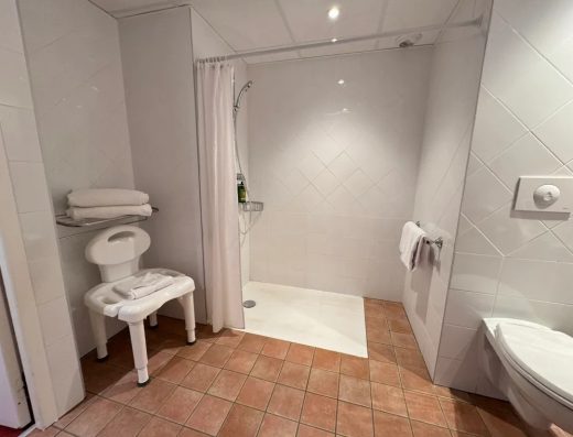 Imagen del interior del baño con ducha a cota cero y asiento.