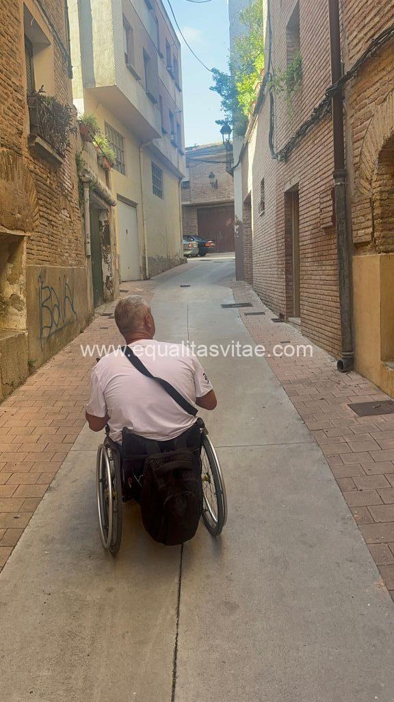 Imagen de una persona en silla de ruedas recorriendo una calle de plataforma única.