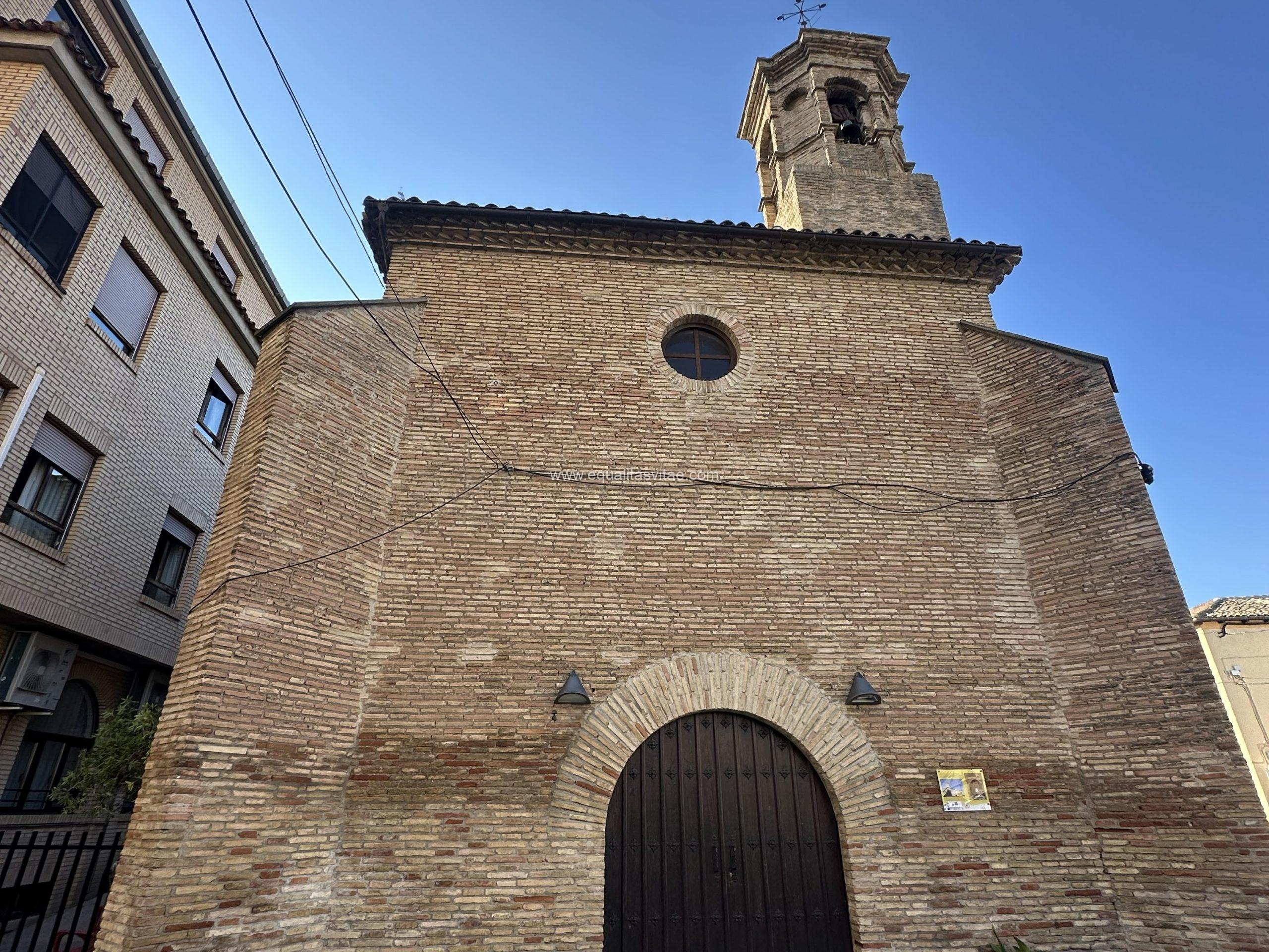 Imagen de la fachada de una iglesia con puerta con arco de medio punto y óculo en la parte superior.