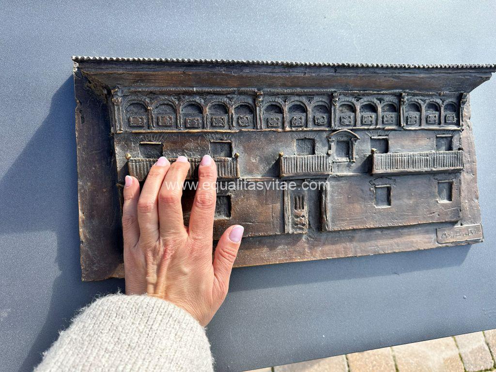 Imagen de una mano tocando la estación táctil con la fachada de una casa barroca.