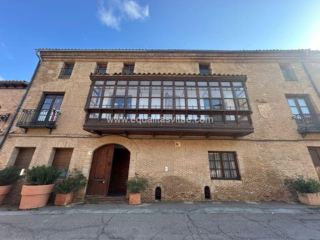 Imagen de la fachada de un edificio barroco con una galería de madera acristalada.