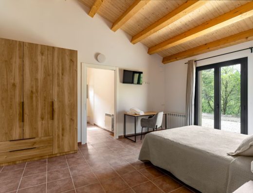 Imagen del la habitación accesible con el armario junto al lado izquierdo de la puerta de entrada y escritorio en el lado derecho. Encima del escritorio una televisión.