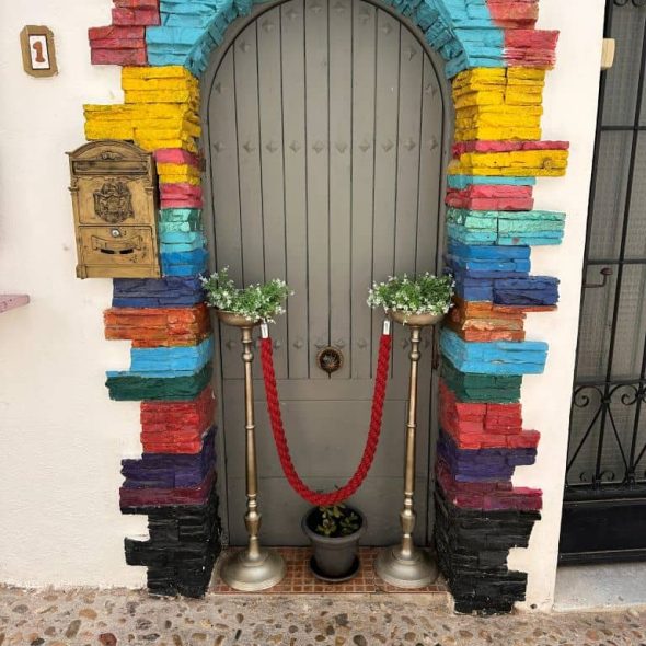 Imagen de una puerta del casco antiguo de Altea con arco de medio punto. Las dovelas están coloreadas con tonos vivos.