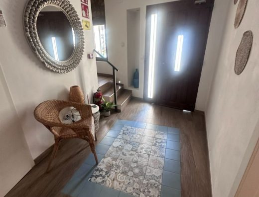 Imagen del hall del hostal. Al fondo de la imagen se encuentra la puerta, a la izquierda un espejo redondo en la pared y bajo el un par de sillas.