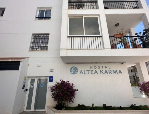 Imagen de la fachada del hostal con dos alturas sobre la planta baja. Fachada blanca con varias terrazas en ambas plantas.