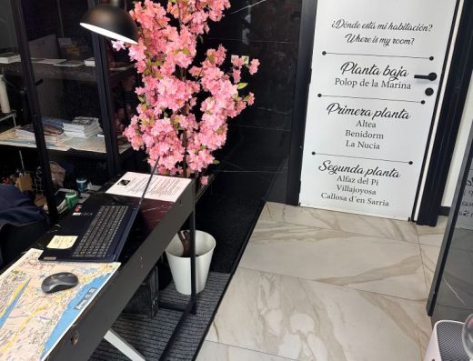 Imagen de la recepción con mostrador a la izquierda. Al fondo un puerta con un directorio.