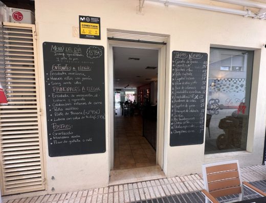 Imagen de la puerta de entrada a cota cero con paneles con la carta a ambos lados.