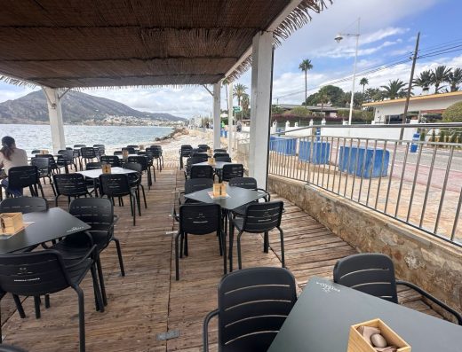 Imagen de una terraza de un chiringuito en la playa bajo una zona de sombra.